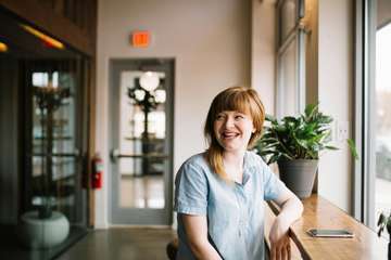 Afb05bb9 unsplash norsyxmhgpi woman sitting in front of brown wooden table norsy 10a006o00000000000001o